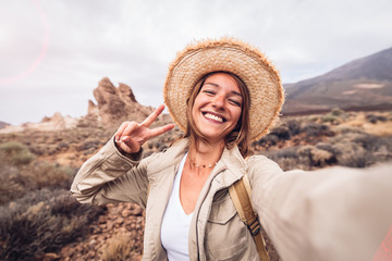 Wall Mural - beautiful happy hiker woman taking a selfie hiking a mountain at vacation. girl wearing hat and back