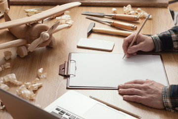 Wall Mural - Craftsman designing a DIY project on a clipboard