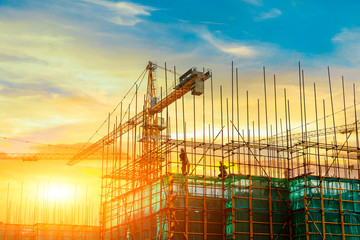 tower crane and building construction site silhouette at sunrise.