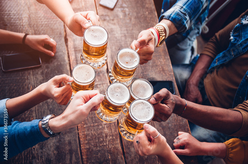 Cuadros en Lienzo Group of people enjoying and toasting a beer in brewery pub - Friendship concept