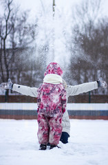 Portrait of a cheerful mother and her daughter in a winter forest at sunset. Focus on the child