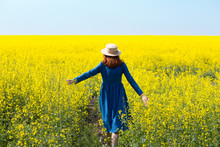 Girl Walking In A Field Of Yellow Rapeseed