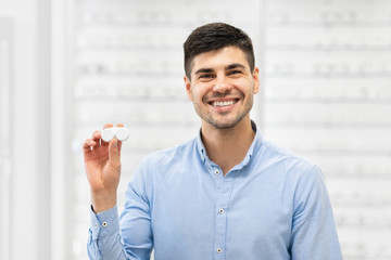 Fototapete - Happy guy holding contact eye lenses container