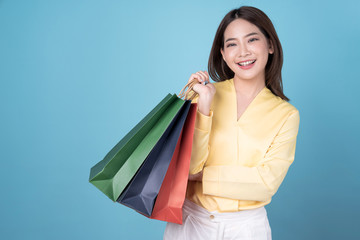 Asian woman are holding shopping bags with face happily, isolated on blue background. 