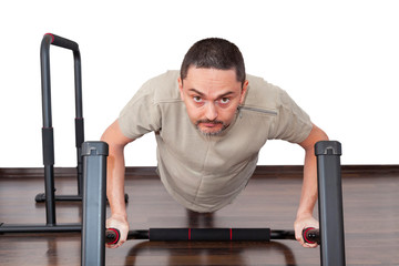 Home workout. Normal guy doing biceps and triceps training in the living room gym. Man doing Parallel Bar Exercises to Build Amazing Body-weight Strength