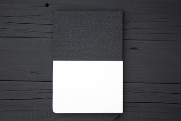 Blank notebook on black wooden table.  Black and white notebook