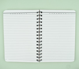 Wall Mural - View of an open white spiral paper notebook placed on top of a paper background