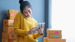 © sutthinon602 - Startup small business SME, Entrepreneur owner using smartphone or tablet taking receive and checking online purchase shopping order to preparing pack product box. Selling online ideas concept