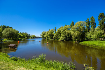 Wall Mural - Beautiful rural landscape. Blue sky and green trees reflecting in the water, boats float on the calm water of the river.