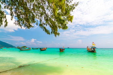 Long tail boats in small harbor at Ko Lipe island, south Thailand. Tropic and exotic island is symbol of tropical paradise, part of Tarutao national nature park. Vibrant colors, turquoise water.