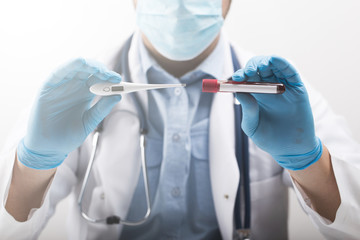 portrait of male doctor holding thermometer in gloves