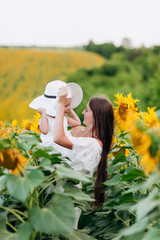 Wall Mural - mother's day. Happy mother with the daughter in the field with sunflowers. mom and baby girl having fun outdoors. family concept.