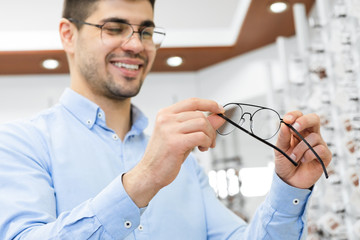 Portrait of handsome young guy choosing spectacles