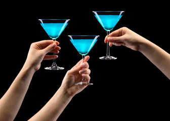 Poster - Set of hands holding blue martini glass isolated on black.