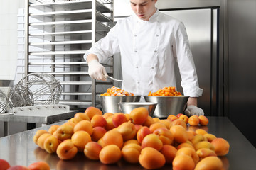 pastry chef at work in professional kitchen, makes apricot jam for the cake or for the croissants, on stainless steel worktops