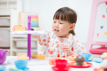 Wall Mural - toddler girl prerend play preparing tea party at home