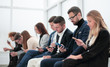 © ASDF - group of young business people with smartphones sitting in a row.