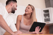 © ASDF - Young couple with digital tablet sitting in kitchen
