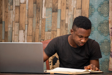 young black man studying at home using his laptop, receiving lectures online
