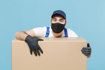 Delivery man in cap t-shirt uniform sterile face mask gloves isolated on blue background studio. Guy employee courier hold cardboard box Service quarantine coronavirus virus covid-19 2019-ncov concept