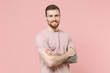 © ViDi Studio - Smiling young bearded tattooed man guy in pastel casual t-shirt posing isolated on pink wall background studio portrait. People emotions lifestyle concept. Mock up copy space. Holding hands crossed.