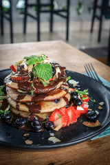 Wall Mural - Pancakes with banana, blueberries, strawberries and chocolate sauce