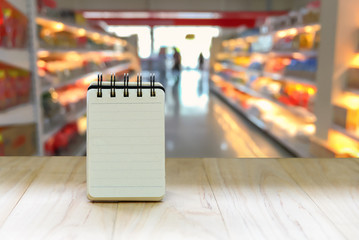 Mock up small note book paper (notepad) stand on wood table for writing an information with copy space