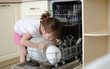 © Natali Tikhonova - Girl puts dirty dishes in the dishwasher