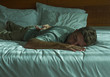 © TheVisualsYouNeed - lifestyle portrait of young attractive tired and exhausted man lying down on bed sleeping during the day with sunlight filtering in the bedroom