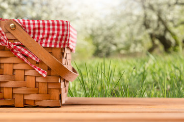 Wall Mural - Picnic basket on a wooden table, against the backdrop of the landscape. Rest and picnic. Weekend or vacation. Concept of summer mood.