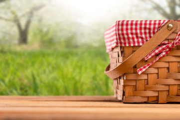 Picnic basket on a wooden table, against the backdrop of the landscape. Rest and picnic. Weekend or vacation. Concept of summer mood.