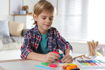 Poster - Little boy playing with plasticine at table indoors. Creative hobby