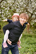 © Oleg - Father plays with his daughter in a flowering garden. Against the background of green grass and flowering trees.