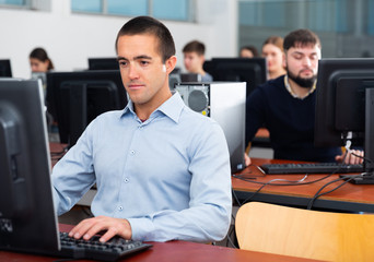 Wall Mural - Portrait of female and male students working on computers in classroom