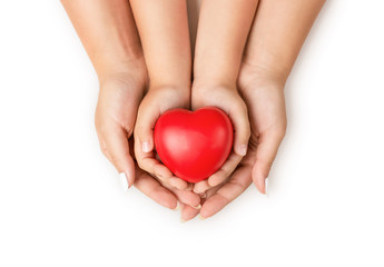 Canvas Print - Love, family concept. Close up of mother and children hands holding red rubber heart together isolated on white background