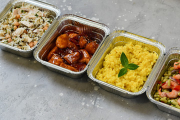 Wall Mural - Food delivery. Different aluminium lunch box with healthy food risotto, chicken with chickpeas and rice, salmon and spinach, chicken teriyaki, shrimp and green beans. airline meals snacks. takeaway