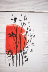 Sticker - Top view of paper with Japanese painting with red sun and branches on wooden background