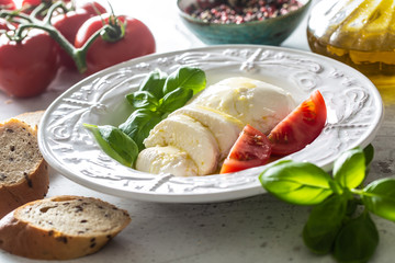 Wall Mural - Mozzarella cheese tomatoes basil and olive oil. Caprese salad - italian or mediterranean meal or appetizer