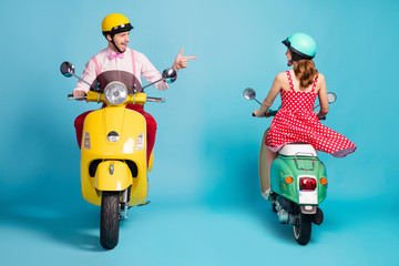 Sticker - Full body photo of interested guy driving vintage moped blink opposite riding lady flirty handsome meet pretty girl direct finger wear retro clothes headgear isolated blue color background