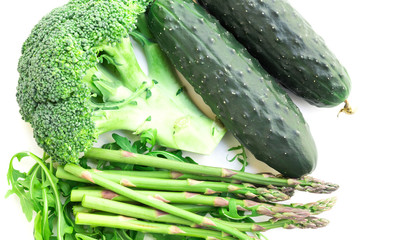 still life from green farm vegetables, arugula, broccoli, asparagus and cucumbers on white background