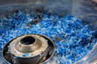 Blue plastic recycled parts material made of blue colored  bottle caps in a grinder ready to be used for new circular plastic products creating awareness for the use of plastic