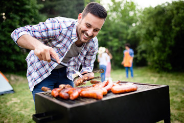 Wall Mural - Handsome male preparing barbecue, grill outdoors for friends