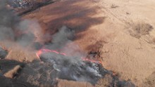 Top view and flying over the field with a line of fire. Epic video shooting, smoke clouds, the spread of fire. Deforestation, burning of dry grass. Climate change and ecology. Uncontrolled rural fire.