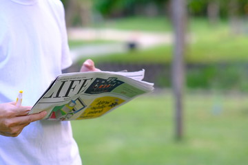 Young Man reading a newspaper in the park