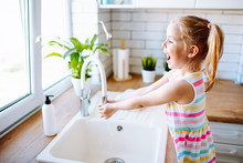 Blonde Toddler Girl Washing Hands In The Light Kitchen Before Eating. Hygiene And Healthcare Concept.
