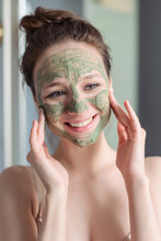 Girl Applies A Green Mask Of Clay, Minerals And Salts To Her Face. Home Light Bathroom. Natural Skin Care. Vegetable Vegan Cosmetics. Lovely Young Girl Smiles.