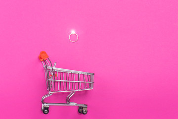 wedding ring sparkles over a basket. on pink background