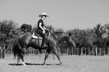 Poster - Western lifestyle of cowgirl in black and white, riding horseback with Texas landscape in background.