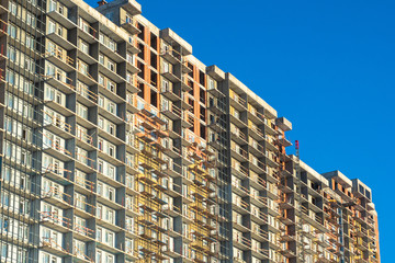 Multi-storey building under construction against the blue sky. Vacancies for builders. Sale of apartments in new houses. Primary real estate. Large selection of new apartments.