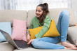 Girl smiling on a couch looking at a laptop